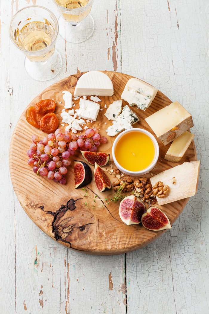 Cheese board with grapes, figs, honey, and nuts