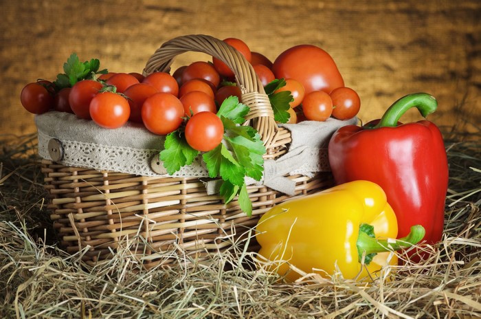 Tomatoes and Bell Peppers in a Wicker Basket on Straw