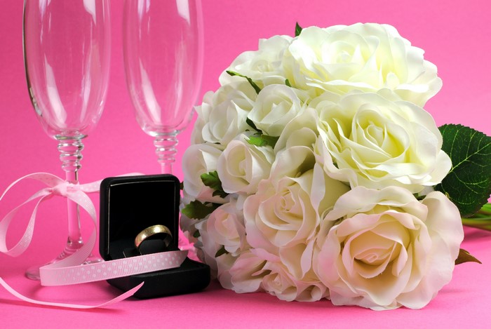 White Roses, Ring, and Champagne Glasses on Pink Background