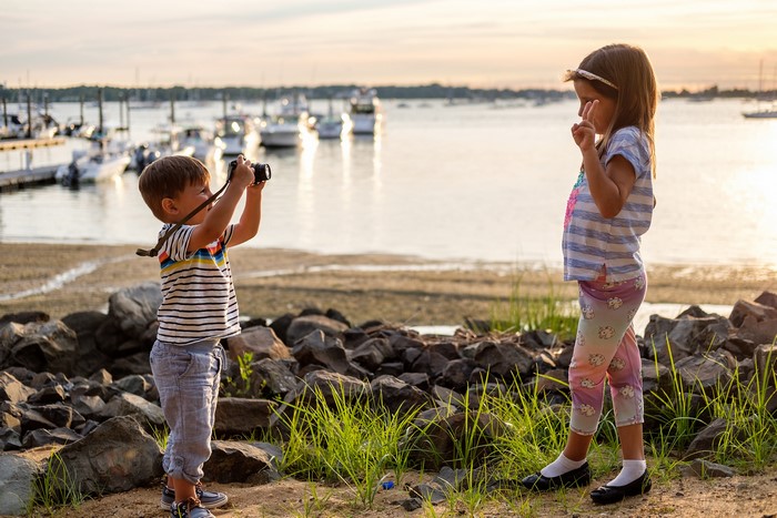 Boy taking a photo of a girl by the water