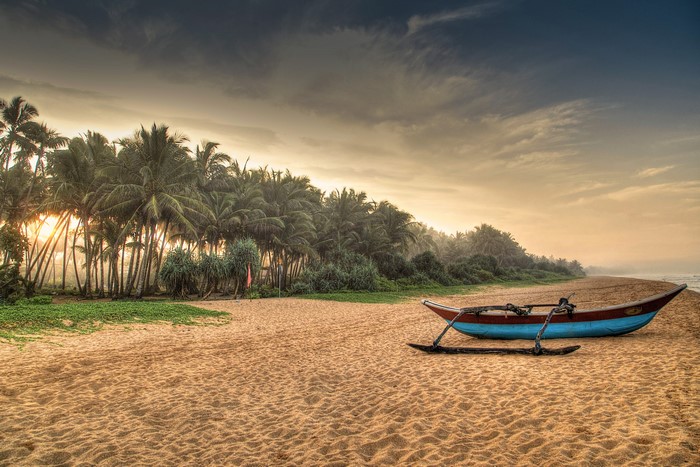 Traditional fishing boat on a sandy beach in Induruwa, Sri Lanka