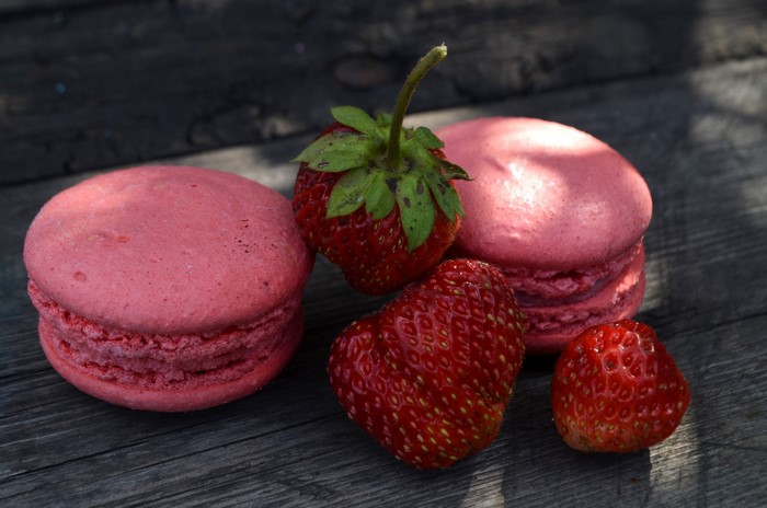 Pink macarons and strawberries on a wooden table