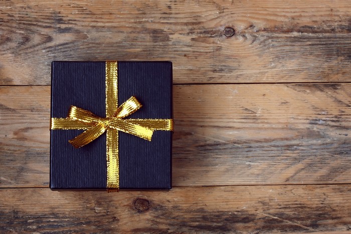 Dark blue gift box with gold ribbon on wood planks