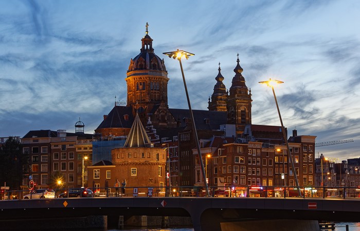 Amsterdam canal bridge at dusk with church