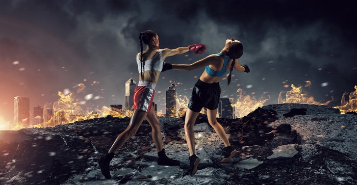 Two female boxers fighting in a burning city