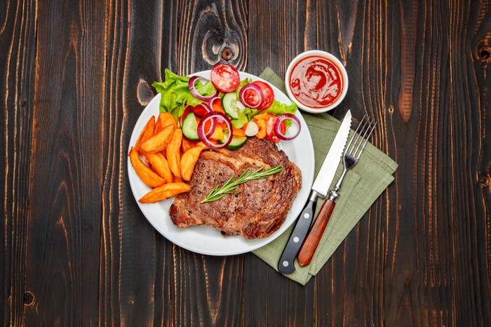 Steak with fries, salad, and ketchup on a plate