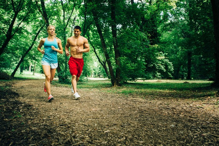 Two people running in a forest