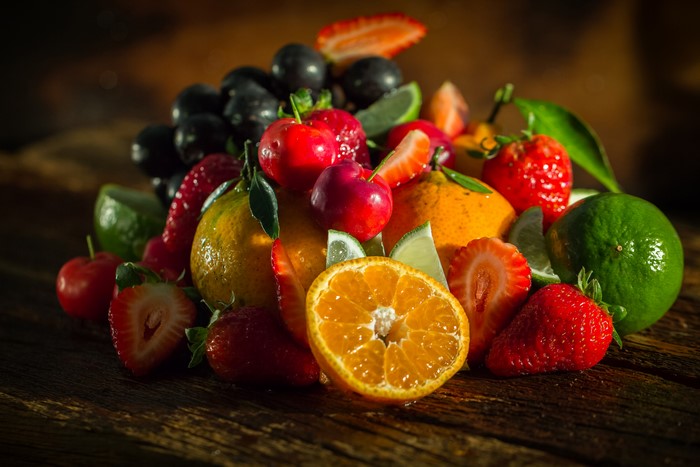 Assortment of fresh fruits including strawberries, cherries, oranges, limes, and grapes