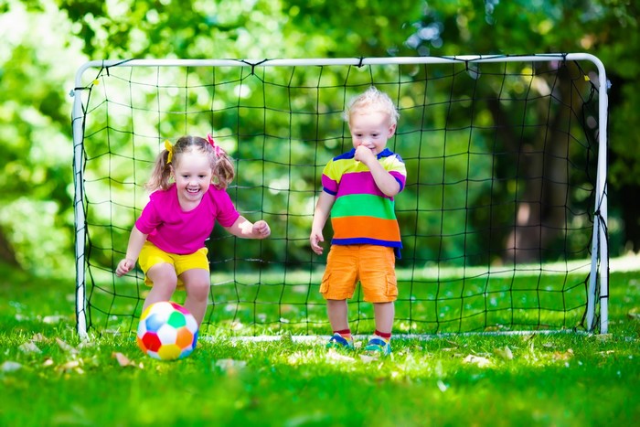 Two children playing soccer in a backyard