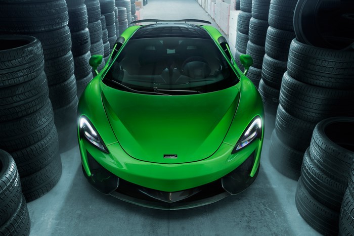 Green McLaren 570GT parked between stacks of tires