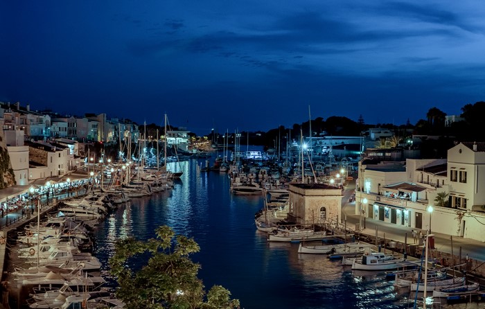 Ciutadella harbor at night with boats and buildings