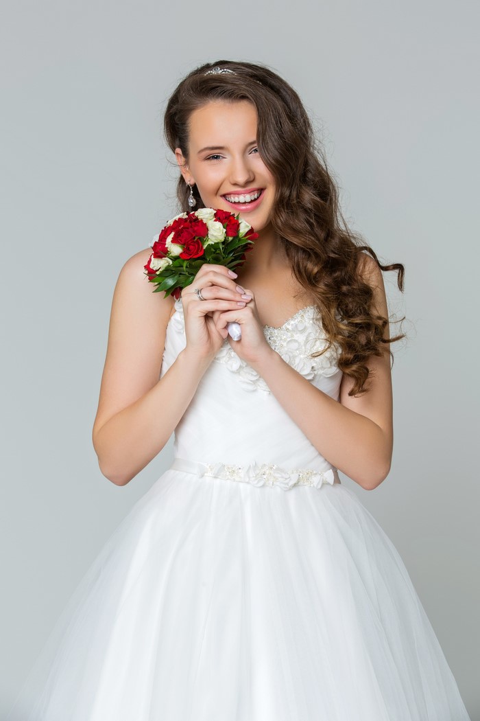 Bride holding a bouquet of red and white roses