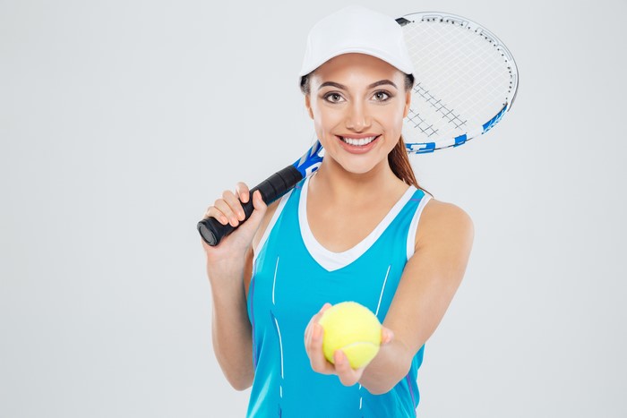 Woman in a blue singlet holding a tennis ball and racket