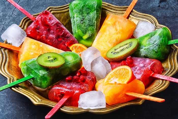 Assortment of colorful fruit popsicles with ice and fruit slices