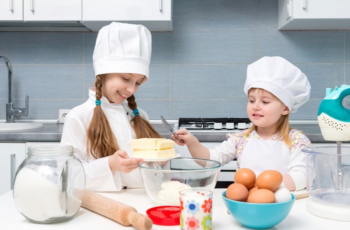 Two young girls in chef hats baking