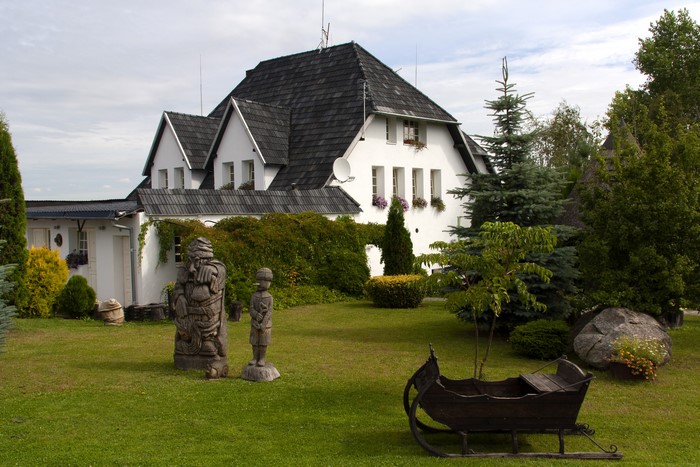 White house with wooden sculptures and sleigh in yard