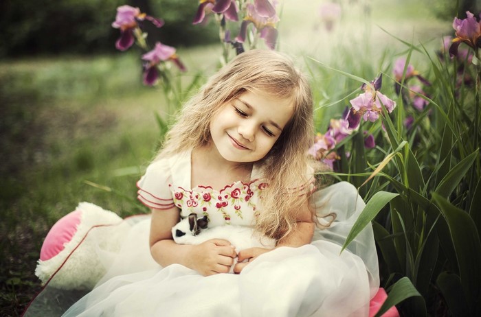 Young girl holding a rabbit in a garden