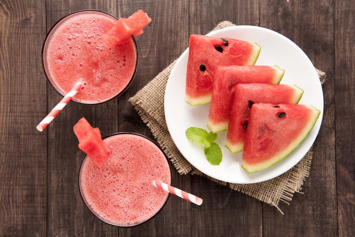 Watermelon juice with watermelon slices on a wooden table