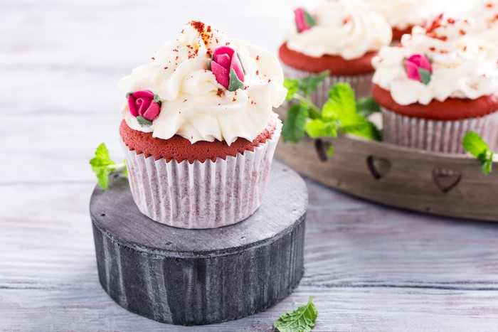 Red velvet cupcakes with cream cheese frosting and rose decorations