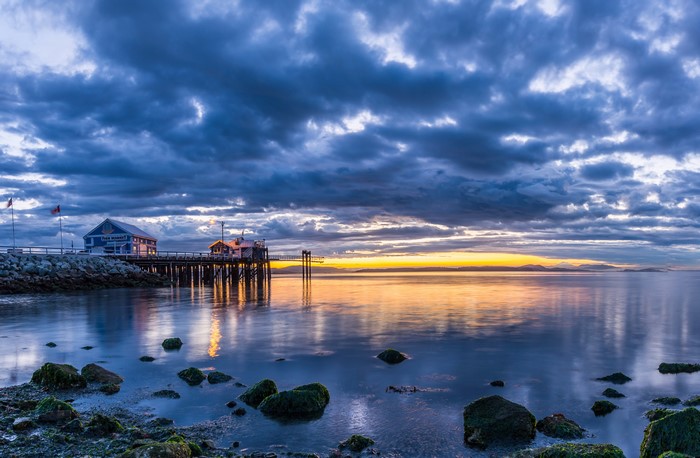 Pier and buildings at sunset with dramatic clouds