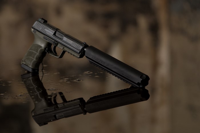 Pistol with suppressor on reflective surface