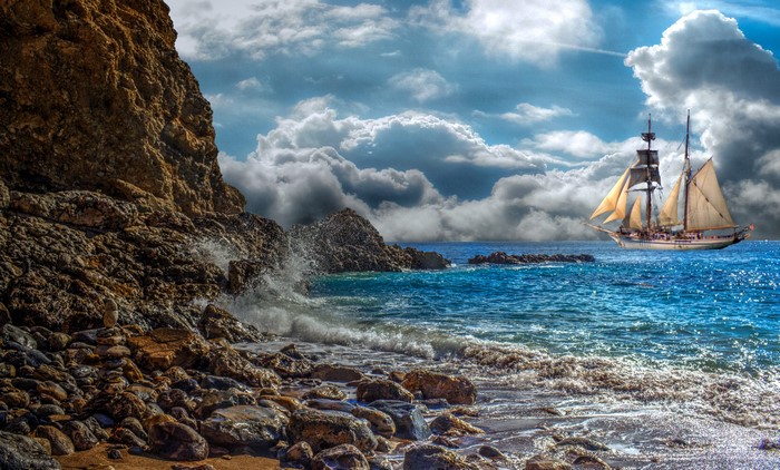 Sailboat on the sea near rocky coast with clouds