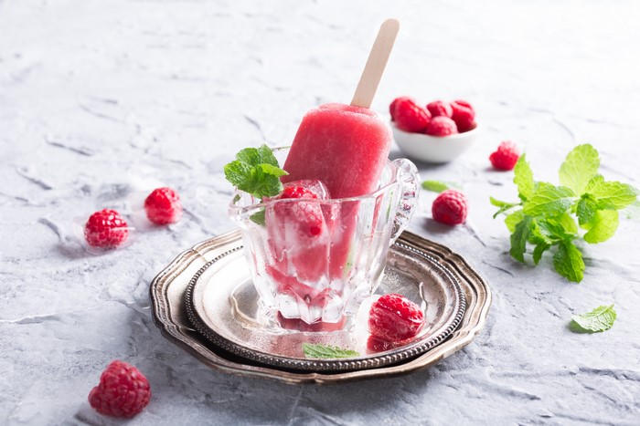 Raspberry popsicle in a glass cup with mint and raspberries