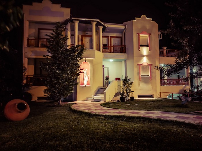 Building at night with a statue and a large pot