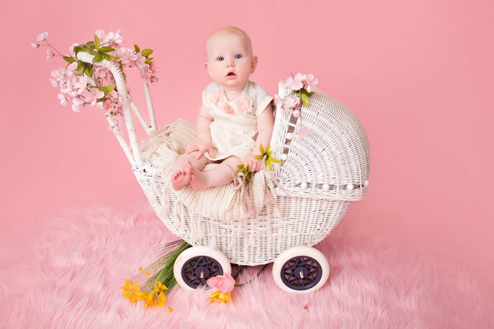 Baby in a wicker pram with pink flowers