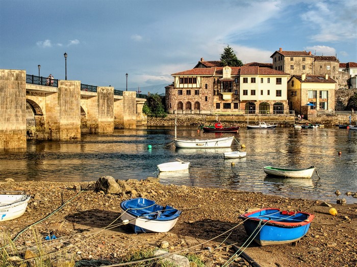 Boats on the river with a stone bridge and buildings in San Vicente de la Barquera, Spain
