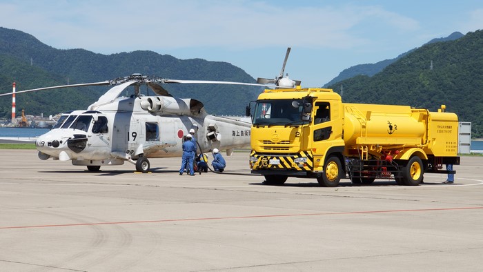 Helicopter refueling by yellow tanker truck at airport