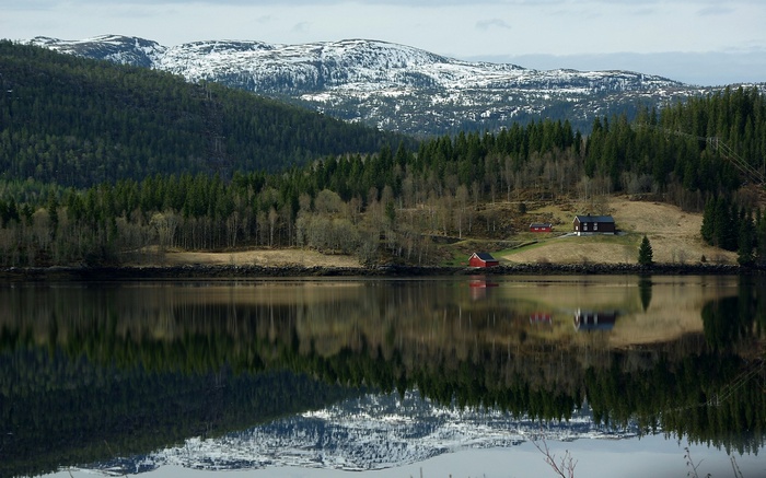 Houses by a lake with snow-capped mountains