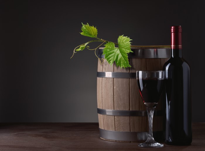 Wine bottle, glass, and barrel with grape leaves