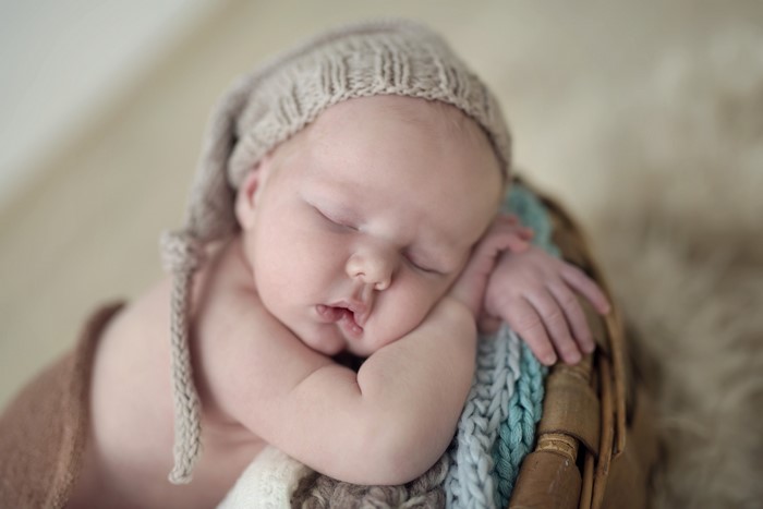 Baby sleeping in a basket wearing a winter hat