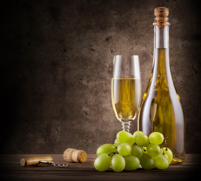 Bottle of white wine with grapes and corkscrew