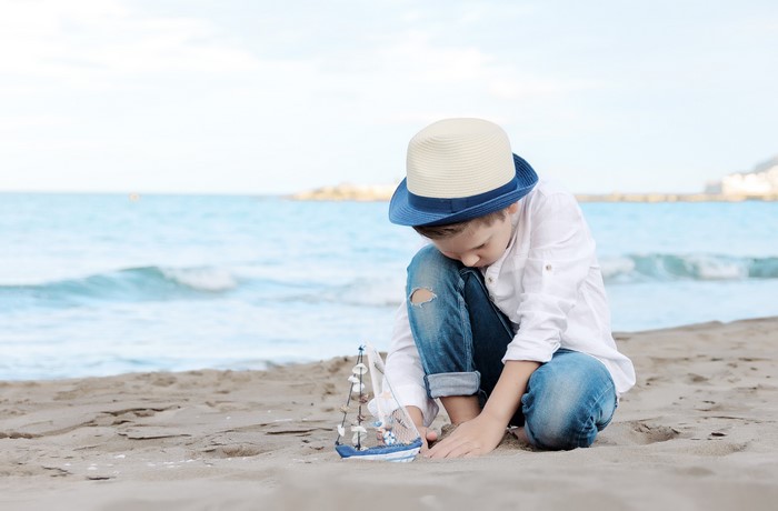 Boy with toy ship on the beach