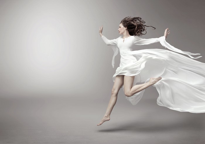 Woman in white dress running on gray background