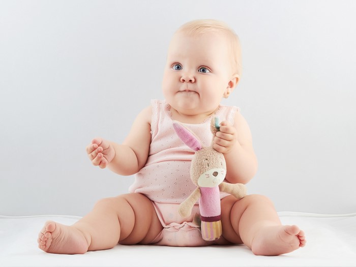 Baby sitting with a stuffed bunny toy