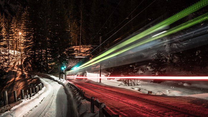 Train light trails at night in a snowy forest