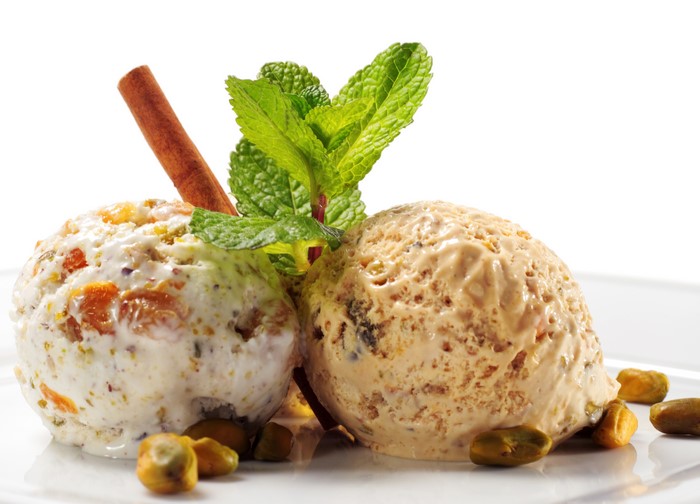 Two scoops of ice cream with pistachios and mint