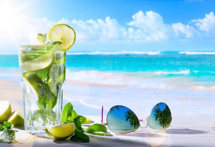 Mojito drink with limes and mint on a beach