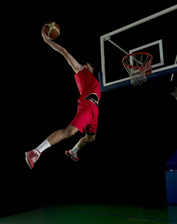 Man in red uniform dunking a basketball