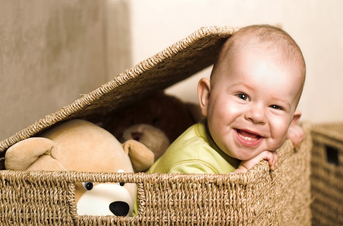 Baby smiling in a wicker basket with teddy bears
