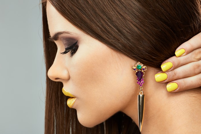 Woman with yellow nails and ornate earring