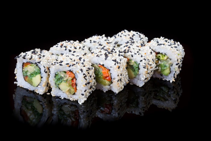 Sushi rolls with sesame seeds on black background