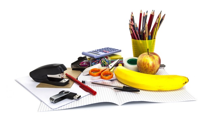 School supplies and fruit on a white background