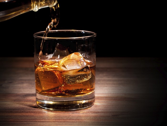 Whisky being poured into a glass with ice