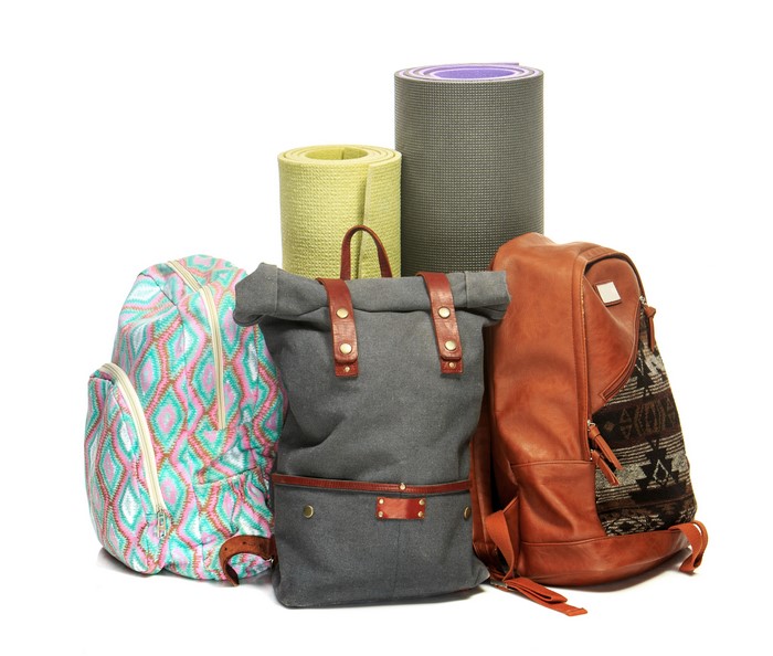 Three backpacks and yoga mats on white background