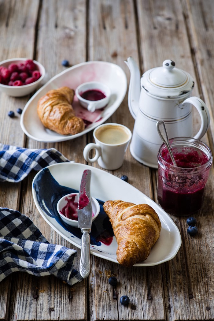 Breakfast with croissants, jam, coffee, and raspberries