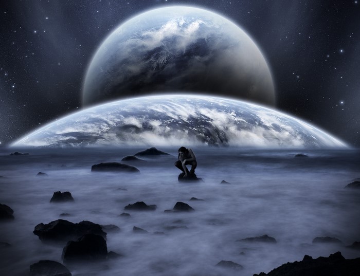 Man crouching on rocks with planets in the sky